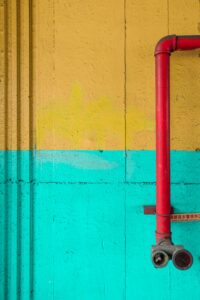 Brightly painted wall with a vibrant red pipe, showcasing abstract street art.
